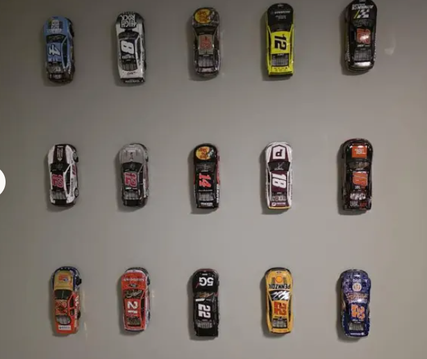 Customer photo: fifteen diecast racing cars mounted in a grid on a gray wall